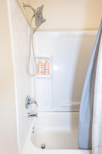 a bath tub with a shower head and a sink at LUX - Downtown Oasis - Pool Table! Free Parking! in Lexington