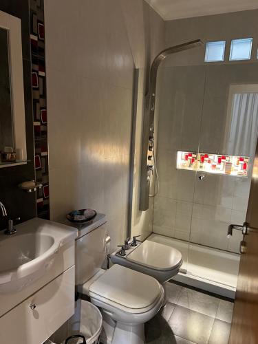 a white bathroom with a toilet and a sink at Casa con pileta y garaje in Roque Sáenz Peña