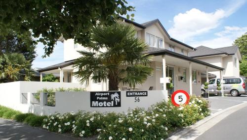 a house with a sign in front of it at Airport Palms Motel in Christchurch