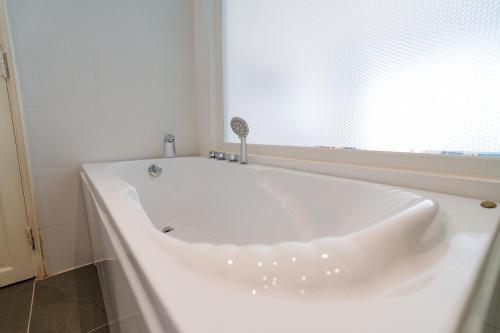 a white bath tub in a bathroom with a window at CHUONG DUONG HOTEL in My Tho