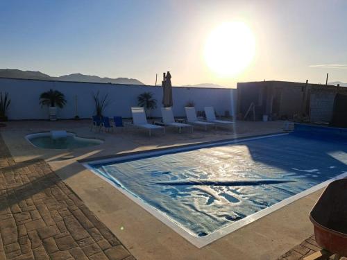 a swimming pool with chairs and the sun in the background at Cabañas Los Laureles Ruta del vino bc in Ensenada