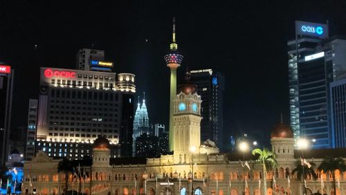 um edifício com uma torre de relógio numa cidade à noite em Sky Suites KLCC Homestay by BIRDY STAY em Kuala Lumpur