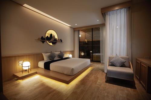 a bedroom with a large bed and a chair at The Arch Phuket Hotel in Ban Ket Ho