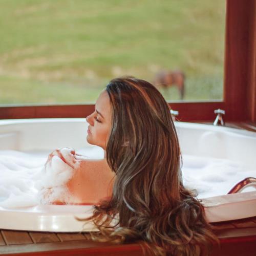 a woman is sitting in a bath tub at Chalé Vista Das Araucárias in Urubici