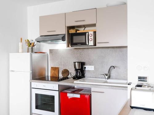 une cuisine avec des armoires blanches et un appareil rouge dans l'établissement Appartement T3 moderne avec WIFI, parking sécurisé et à 300m de la plage - FR-1-409-160, à Narbonne