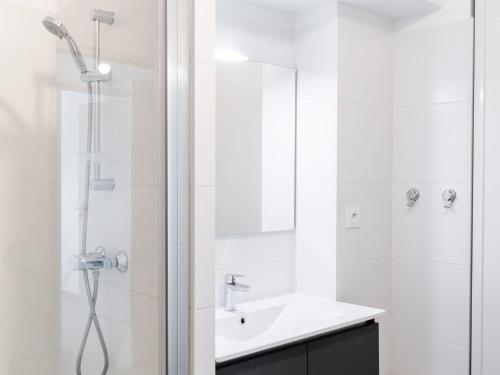 une salle de bain blanche avec une douche et un lavabo dans l'établissement Appartement T3 moderne avec WIFI, parking sécurisé et à 300m de la plage - FR-1-409-160, à Narbonne
