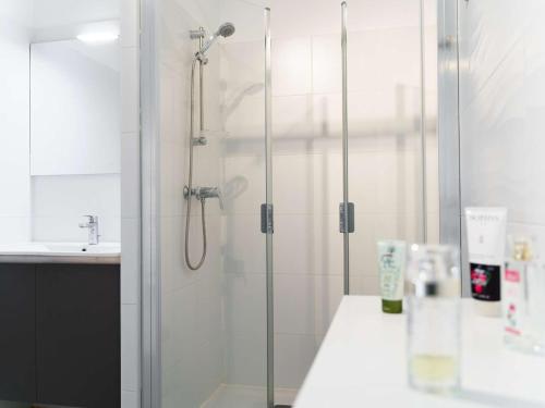 eine Dusche mit Glastür neben einem Waschbecken in der Unterkunft Moderne T3 climatisé, 2 parkings, à 300m de la plage - FR-1-409-165 in Narbonne