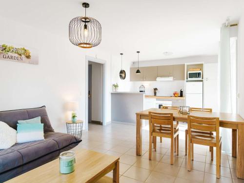 Il comprend un salon et une cuisine avec une table et un canapé. dans l'établissement Charmant T3 à 300m de la plage, Balcons, Parking, Proche Commerces, Narbonne-Plage - FR-1-409-169, à Narbonne