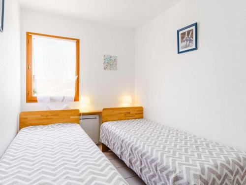 une chambre avec deux lits et une fenêtre dans l'établissement Pavillon T3 rénové, proche plage, 2 chambres, terrasse, garage, WiFi - FR-1-409-170, à Narbonne
