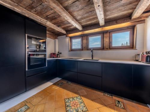 d'une cuisine avec des armoires noires et un plafond en bois. dans l'établissement Chalet familial authentique avec spa, jacuzzi et hammam - Courchevel 1850 - FR-1-613A-26, à Courchevel