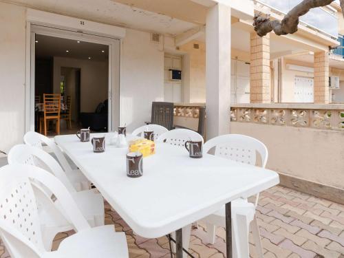 - une table et des chaises blanches sur la terrasse dans l'établissement Appartement T3 climatisé, rénové avec goût, à 150m de la plage, avec terrasse et équipements complets - FR-1-409-204, à Fleury