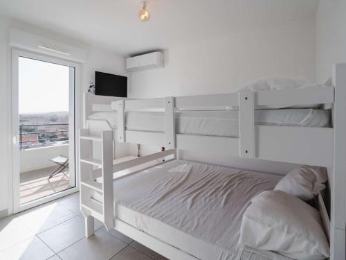 une chambre avec deux lits superposés et une fenêtre dans l'établissement Appartement lumineux et climatisé avec WIFI et parking à Narbonne-Plage - FR-1-409-202, à Narbonne