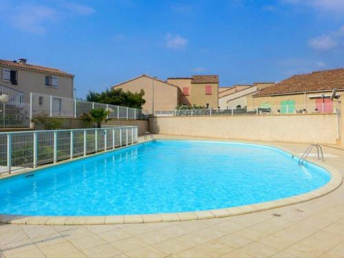 une grande piscine bleue entourée d'une clôture. dans l'établissement Duplex cosy avec piscine et WiFi, proche plage et commerces, pour 4 pers., parking inclus - FR-1-409-213, à Fleury