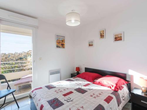 une chambre avec un lit avec des oreillers rouges et une fenêtre dans l'établissement Appartement moderne 3 pièces, à 300m plage, parking, WIFI, Narbonne-Plage - FR-1-409-214, à Narbonne