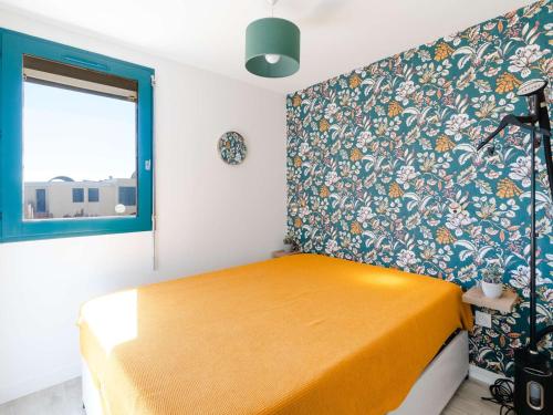 une chambre avec un lit jaune et un mur fleuri dans l'établissement T2 climatisé près plage, parking, cuisine tout équipée, balcon - Gruissan - FR-1-409-227, à Gruissan