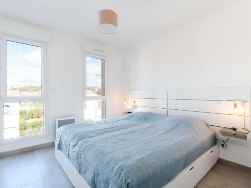 une chambre blanche avec un lit et deux fenêtres dans l'établissement T3 climatisé, proche plage, neuf, WIFI inclus, parking privé - FR-1-409-230, à Narbonne