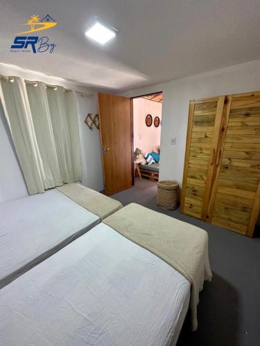 a bedroom with two beds and a door with a person sitting at Casa SRBG - 2 Quartos com Ar - 150m da Praia in Barra Grande