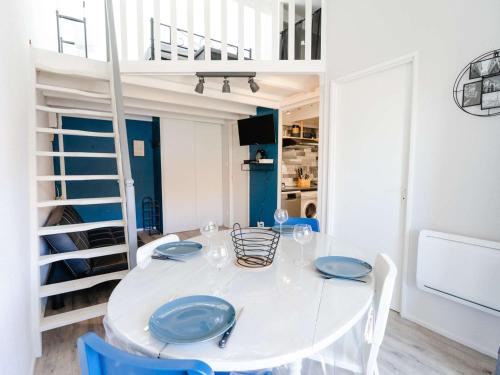 une salle à manger blanche avec une table blanche et des chaises bleues dans l'établissement T2 Mezzanine Narbonne-Plage - 6 Pers, proche plage, parking gratuit, sans animaux - FR-1-409-243, à Narbonne