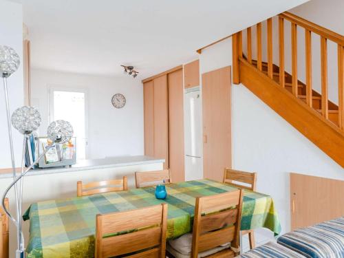 une salle à manger avec une table et des chaises et un escalier dans l'établissement Pavillon 3 pièces avec piscine et parking proche plages - FR-1-409-226, à Fleury