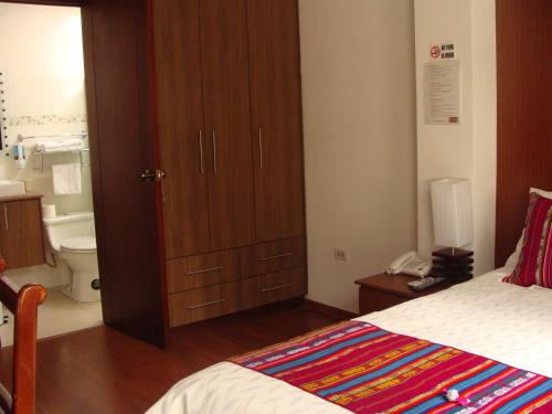 a bedroom with a bed and a cabinet and a bathroom at Hotel Sumaq Kay in Cumbayá
