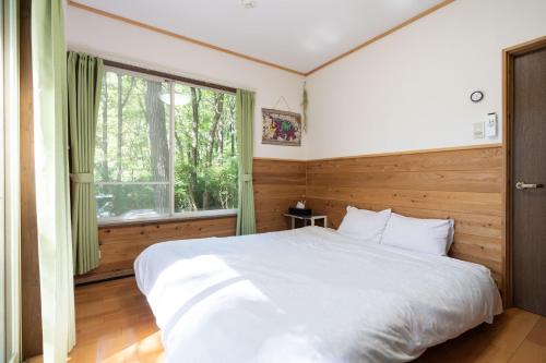 a bedroom with a large white bed and a window at S-villa Nasu 8th in Nasu