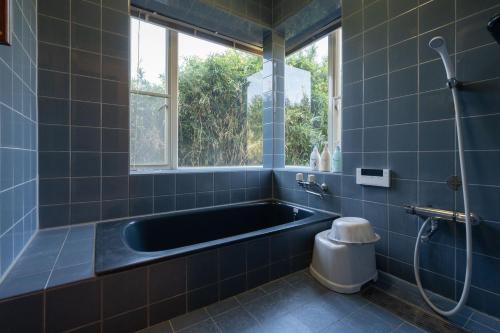 a blue tiled bathroom with a tub and a toilet at S-villa Nasu 11th in Nasu