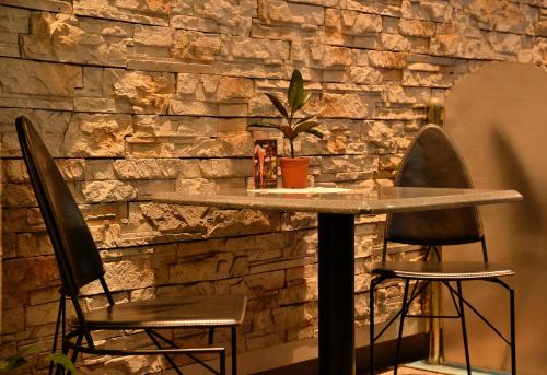 a table and two chairs in front of a stone wall at Nissei Hotel Fukuoka in Fukuoka
