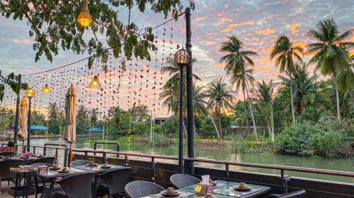 a restaurant with a view of a river and palm trees at DAMNERNPAWA in Bang Khon Thi