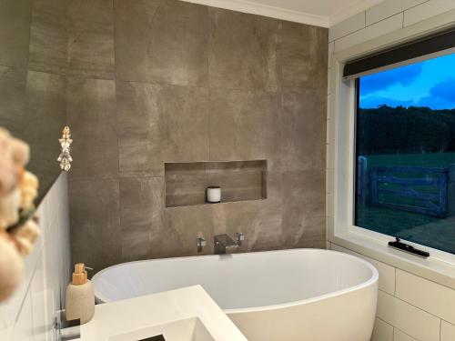 uma banheira na casa de banho com uma janela em PepperTree Farm Stay em Grassy