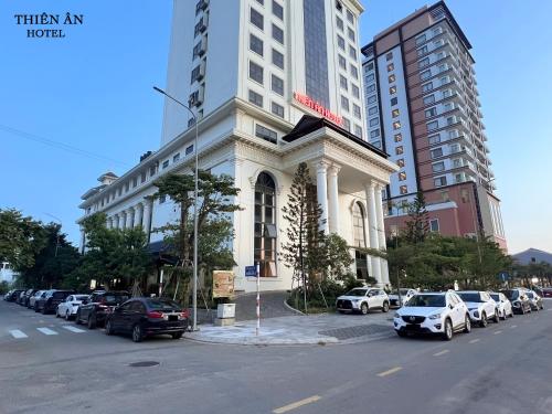 a white building with cars parked in a parking lot at Thiên Ân Hotel in Thôn Dương Phẩm