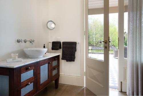 a bathroom with a sink and a mirror and a door at Orchards at Spring Vale Farm in Weatherboard