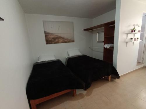 2 Betten in einem Zimmer mit schwarzer Bettwäsche in der Unterkunft Hospedaje La Gloria in Texcoco de Mora