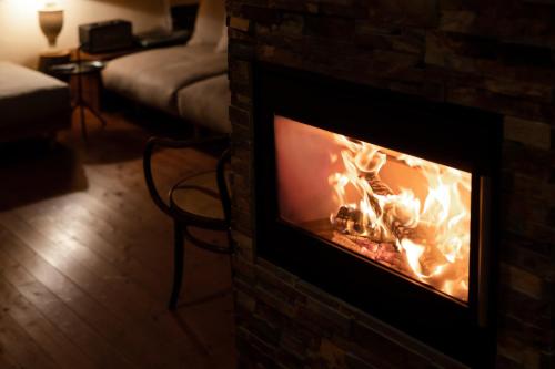 a fireplace with a fire in it in a living room at Lodge Norheim in Asahikawa