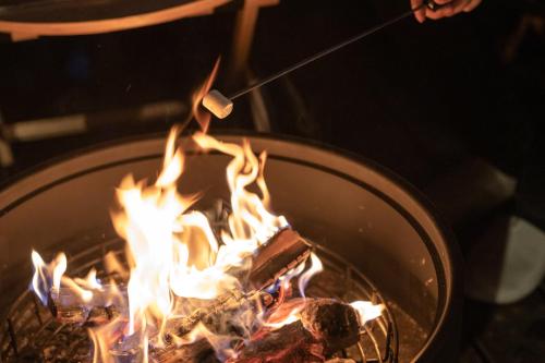 a person is cooking food over a grill with flames at Lodge Norheim in Asahikawa