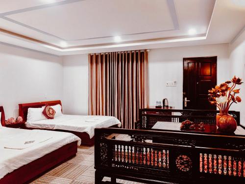 a hotel room with two beds and a table with flowers at Khách sạn Hương Thầm Tây Ninh in Tây Ninh
