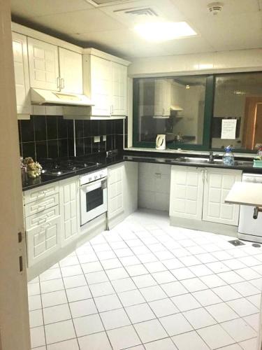 a kitchen with white cabinets and a white tile floor at COUPLES SIZE PARTITION ROOM near FINANCIAL METRO/DIFC in Dubai