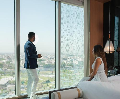 a man and woman looking out of a window in a hotel room at Four Seasons Hotel Kuwait at Burj Alshaya in Kuwait