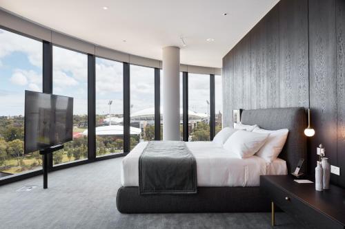 a bedroom with a large bed and a tv in it at Eos by SkyCity in Adelaide