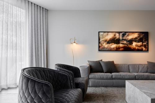 Eos by SkyCity في أديلايد: غرفة معيشة مع كرسيين وأريكة