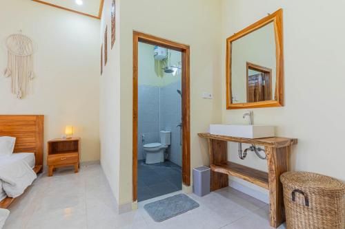 a bathroom with a toilet and a sink and a mirror at Sandz House in Jembrana