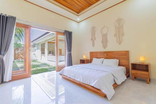 a bedroom with a bed and a large window at Sandz House in Jembrana