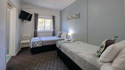 a hotel room with two beds and a tv at Oasis Motel in Peak Hill