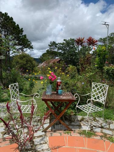 a table with two chairs and a table with flowers on it at Romantic house on a pine hill Dalat in Xuan An