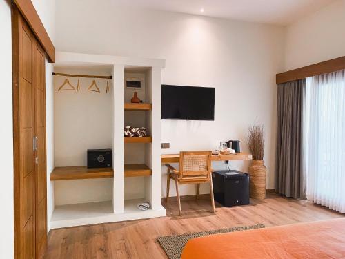 a room with a bedroom with a desk and a television at Reset Lombok Hotel in Kuta Lombok