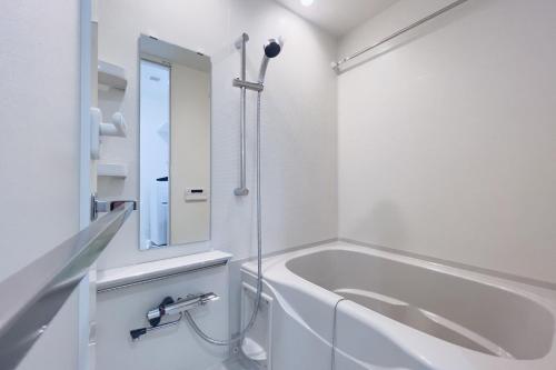 a white bathroom with a tub and a mirror at Sakuramichi Terrace in Tokyo