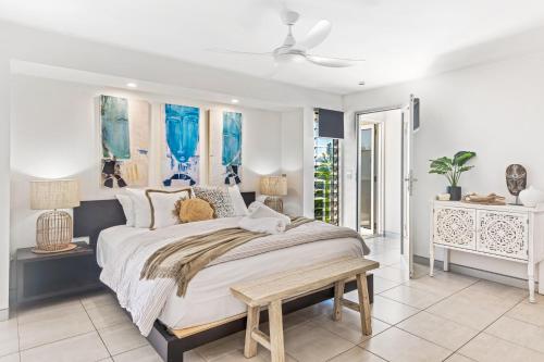 a white bedroom with a large bed and a table at Alex Beach House in Alexandra Headland