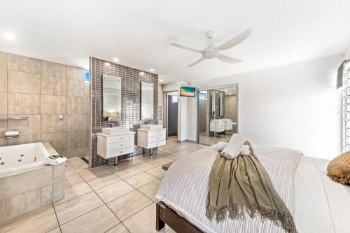 a bedroom with a bed and a bathroom with a ceiling fan at Alex Beach House in Alexandra Headland
