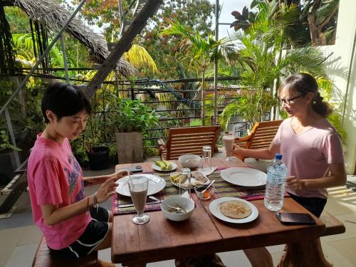 zwei Frauen sitzen an einem Tisch und essen Essen in der Unterkunft Sacred City Tourist Resort in Anuradhapura