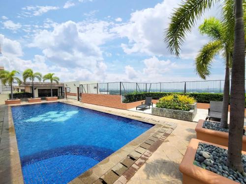 una piscina con palmeras y un edificio en Relaxing Escape at BGC by Max Dwell Studio en Manila