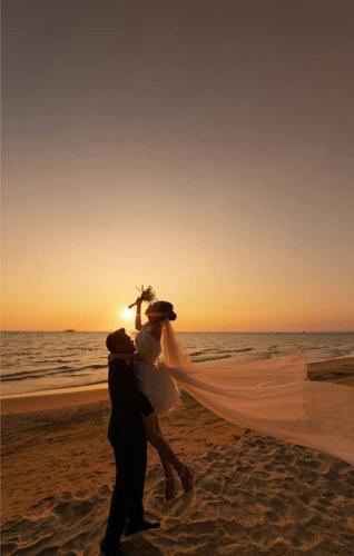 a bride and groom walking on the beach at Golden Lotus Homestay Phú Quốc in Phu Quoc